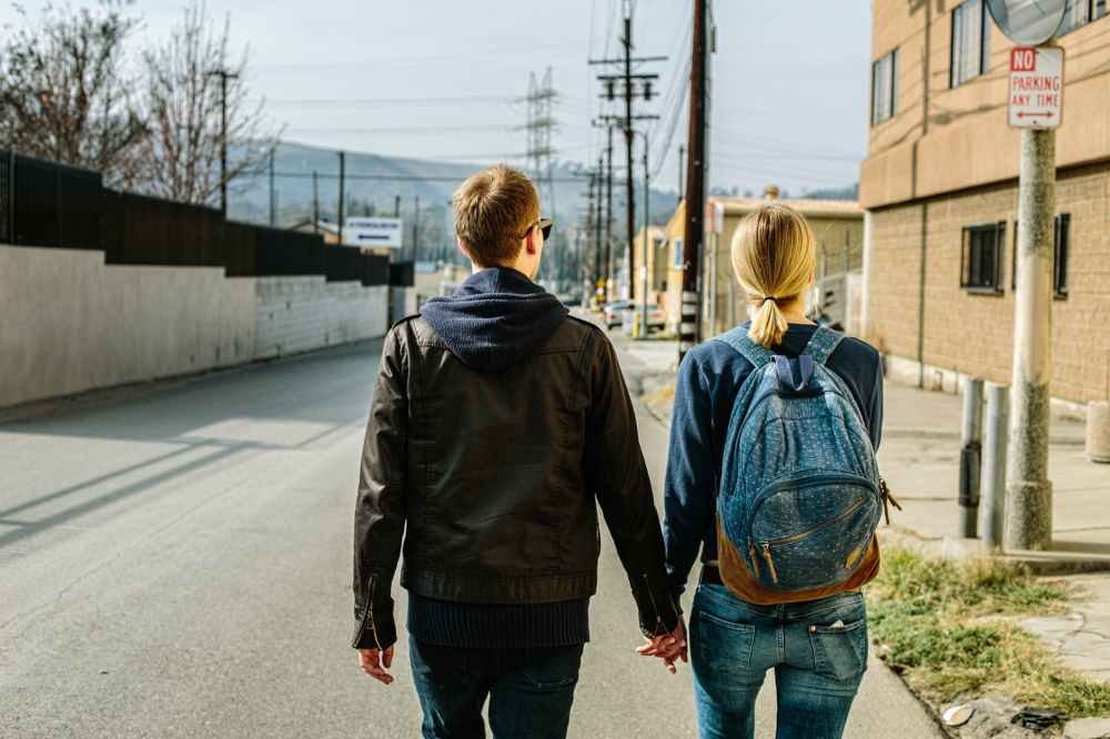 man and woman holding hands while walking during daytime
