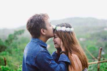 man wearing blue denim jacket while kissing woman s forehead